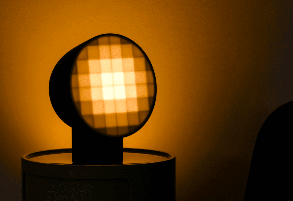 Final version of the Pixel Light by Nicholas Baker, shown in the dark on a side table